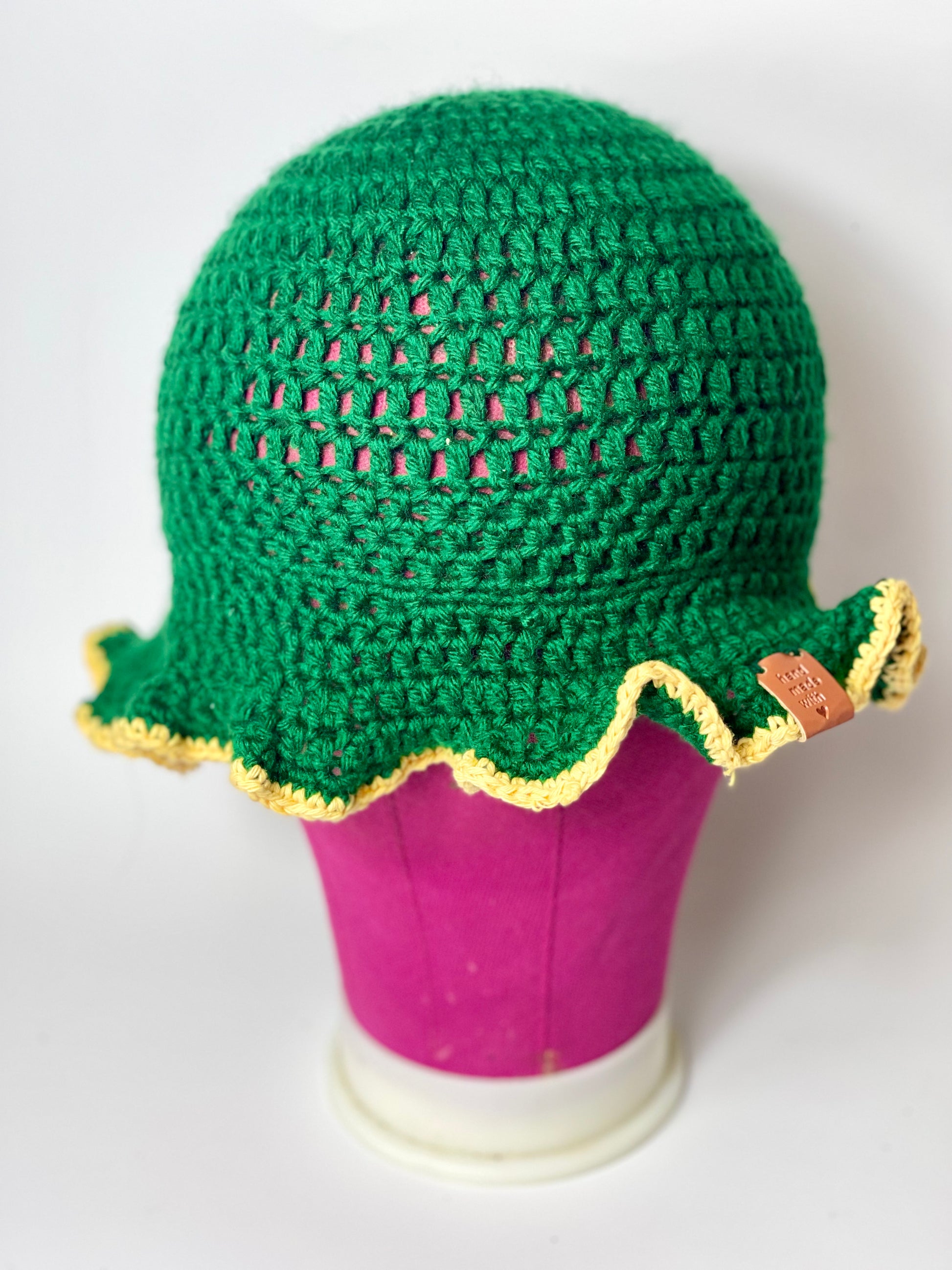 “Detailed view of the ruffled brim on handmade green crochet hat”